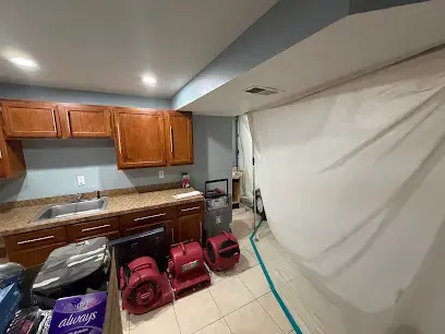 Containment wall and air movers set up in a water-damaged kitchen in Auburn