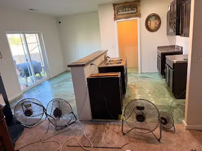 Fans drying a kitchen floor after cabinets were pulled for water damage in Auburn, WA